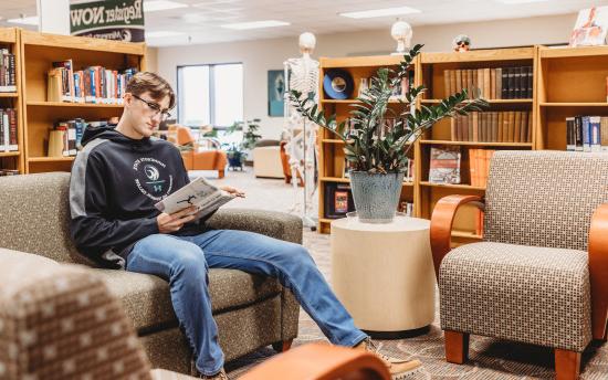 A student reading a book in a study area of the library